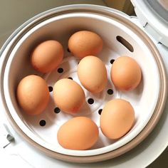 six eggs in a white bowl on top of a counter