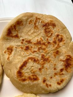 two pita breads sitting on top of a white plate next to sliced bananas