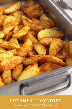 a pan filled with fried potatoes on top of a white countertop next to a knife and fork