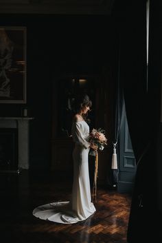 a woman standing in a dark room holding a bouquet