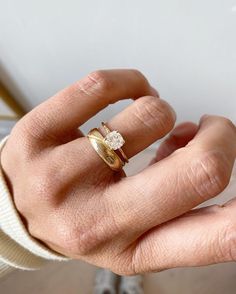 a person's hand with two gold rings on it and one diamond ring in the middle