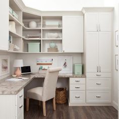 a home office with white cabinetry and marble counter tops, along with wooden flooring