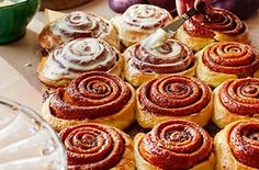 a person is cutting into some cinnamon rolls