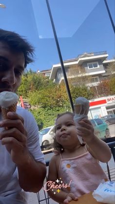 a man holding a cupcake and eating it with a baby in front of him