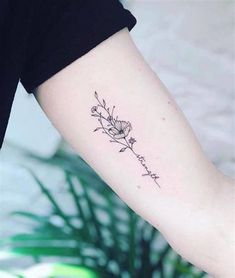 a woman's arm with a small flower tattoo on the left side of her arm