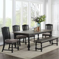 a dining room table with four chairs and a bench in front of a large window