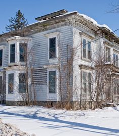 an old white house with snow on the ground