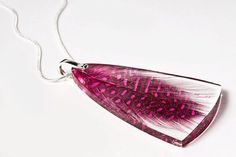 a pink and white feather pendant on a silver chain