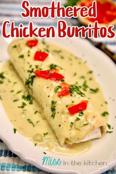 a white plate topped with two enchiladas covered in sauce and garnished with red peppers