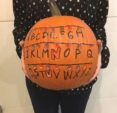 a person holding a pumpkin with writing on it