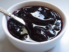 a white bowl filled with black liquid and a spoon in it's side dish