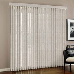 a living room with white vertical blinds on the wall and wood flooring in front of it