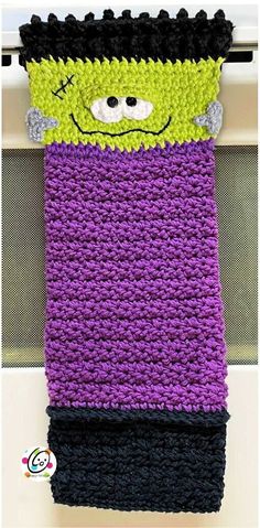 a crocheted purple and black towel hanging from a hook