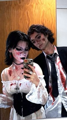 a man and woman dressed up as zombies taking a selfie in front of a mirror