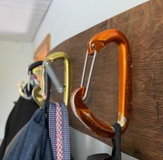 an orange carafe hanging from a hook on a wooden coat rack next to clothes