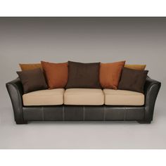 a brown and tan couch with pillows on it's back end, against a gray background