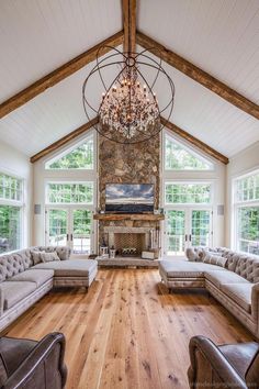 a living room with couches and a chandelier hanging from the vaulted ceiling