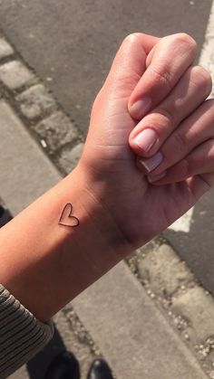 a woman's arm with a small heart tattoo on her left wrist and the word love written in it