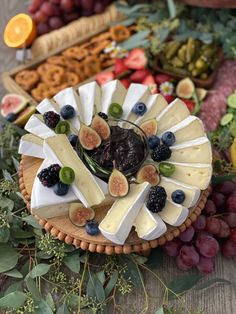 an assortment of cheeses and fruit arranged on a platter