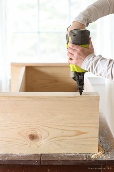 a person using a power drill to attach the top of a piece of plywood