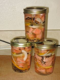 three jars filled with food sitting on top of a wooden table next to a wall