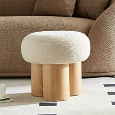 a white ottoman sitting on top of a rug next to a couch and coffee table