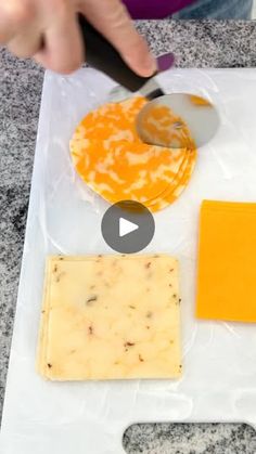 someone is cutting cheese with a knife on top of a plastic bag and another piece of cheese next to it