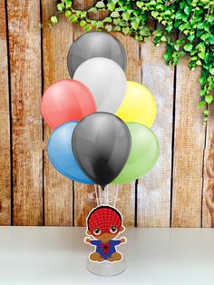 a bunch of balloons that are sitting on a table in front of a wooden wall