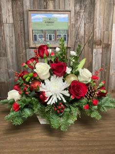 a bouquet of red and white flowers sitting on top of a wooden table