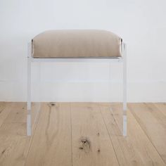 a white bench sitting on top of a hard wood floor next to a white wall