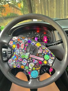 a person sitting behind the wheel of a car with colorful stickers on it's steering wheel