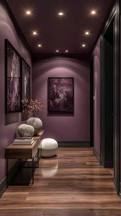 a hallway with purple walls and wooden flooring is lit by recessed lights above the console table