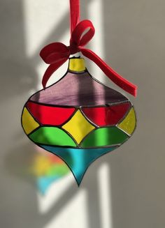 a stained glass ornament hanging from a red ribbon