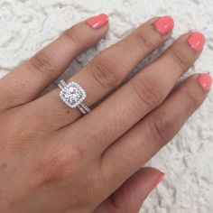 a woman's hand with an engagement ring on top of her finger and pink nail polish