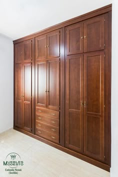 an empty room with wooden cabinets and tile flooring in the center, along with white walls