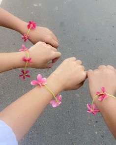 two girls are holding hands with pink flowers on their wristbands and one girl is wearing a white shirt