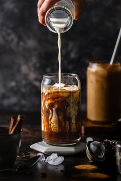 someone pouring coffee into a glass with ice