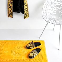 a pair of slippers sitting on top of a yellow rug next to a white chair