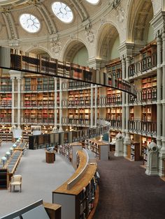 the interior of a large library with many bookshelves and clock mounted to the ceiling