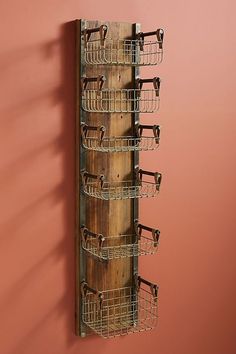 a wall mounted rack with multiple baskets on it's sides against a pink wall