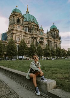 a woman sitting on the edge of a stone bench in front of a large building