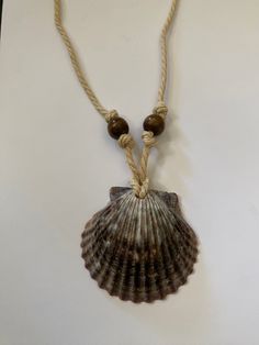 a seashell is hanging from a rope on a white surface with two brown beads