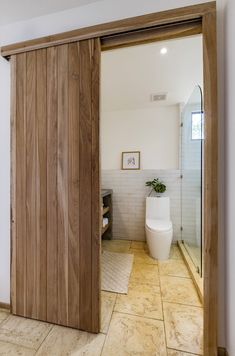 an open door leading to a bathroom with a toilet in the corner and a potted plant next to it