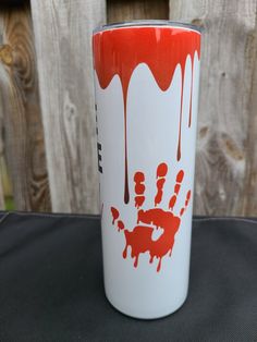 a red and white coffee cup sitting on top of a black table next to a wooden fence