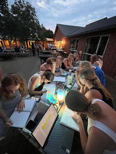 a group of people sitting around a table with laptops on it and papers in front of them