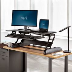 two computer monitors sitting on top of a wooden desk