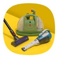 a green and white steam mop sitting on top of a yellow table next to a vacuum cleaner