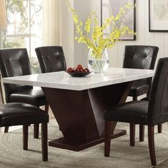 a dining table with chairs around it and a bowl of fruit on the table top