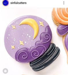 two decorated cookies sitting next to each other on top of a white table with purple icing