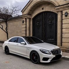 a white mercedes s - class parked in front of a building with black rims